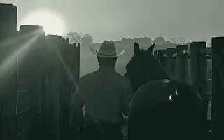 Fim de tarde no curral, com um cavalo e um cavaleiro em contraluz baixa